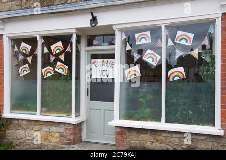 Drapeaux et tableaux d’arcs-en-ciel pour enfants dans les fenêtres, dans un village rural, remerciant les travailleurs essentiels qui ont servi pendant la pandémie de Covid 19. Dorset, Royaume-Uni. Banque D'Images