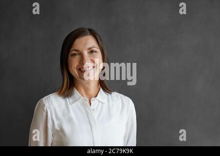 Portrait d'une femme d'affaires souriant tout en se tenant seule devant un tableau blanc dans un bureau Banque D'Images