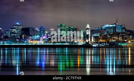 Downton Montréal en hiver. Prise de vue nocturne à exposition longue avec les lumières de la ville reflétées dans le fleuve Saint-Laurent. Banque D'Images