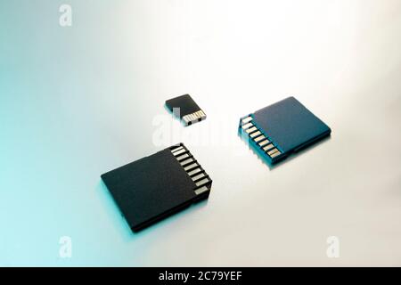 Gros plan de trois cartes SD ou cartes mémoire pour appareils photo et appareils numériques et sur une surface métallique grise, mise au point sélective, filtre vert Banque D'Images