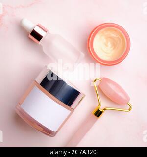 Bouteille cosmétique et accessoires pour le soin du visage sur fond rose. Design d'emballage des produits de beauté. Banque D'Images