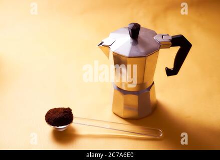 cafetière geyser avec café frais et cuillère sur fond jaune Banque D'Images