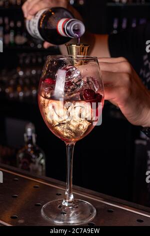 Processus de préparation d'un cocktail alcoolique. Un barman mâle verse de l'alcool dans un verre. Banque D'Images