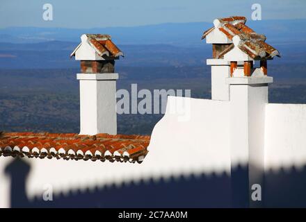 Monsaraz, Evora, région de l'Alentejo, Portugal. Jeu de lumière et d'ombre sur une façade blanchie à la chaux et des cheminées dans la ville fortifiée historique au sommet d'une colline. Banque D'Images