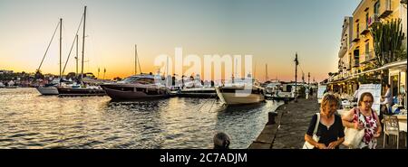 ISCHIA PORTO (NA), ITALIE - 28 JUIN 2020 : bateaux amarrés flottant dans la marina tandis que les touristes se prominent devant les restaurants et les boutiques Banque D'Images