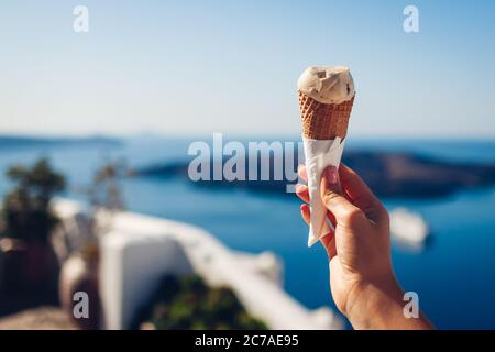 Glace en cône. Fille mangeant de la glace de la tenant sur le fond de la mer de Caldera sur l'île de Santorini. Vacances d'été Banque D'Images