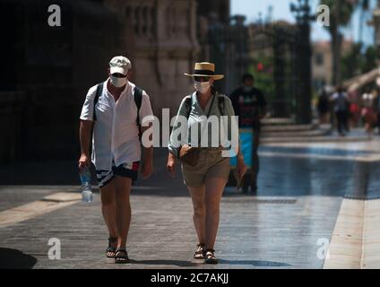 Malaga, Espagne. 15 juillet 2020. Un couple de touristes portant des masques de visage marchant dans les rues pendant la première journée d'utilisation obligatoire des masques de visage.de nouvelles infections à coronavirus en Espagne après l'assouplissement des restrictions ont poussé le gouvernement régional à imposer l'utilisation obligatoire des masques de visage en plein air et les lieux fermés et les plages, même lorsqu'ils observent une distance de sécurité entre les personnes. Cette mesure vise à freiner la propagation de la pandémie du coronavirus. Crédit: Jesus Merida/SOPA Images/ZUMA Wire/Alay Live News Banque D'Images