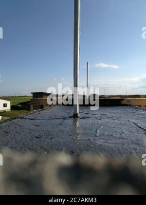 Vis métalliques insérées dans le béton humide pour la fixation sur le toit d'une maison individuelle Banque D'Images