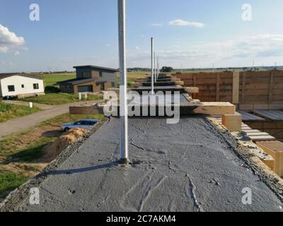 Vis métalliques insérées dans le béton humide pour la fixation sur le toit d'une maison individuelle Banque D'Images
