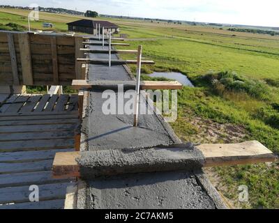 Vis métalliques insérées dans le béton humide pour la fixation sur le toit d'une maison individuelle Banque D'Images