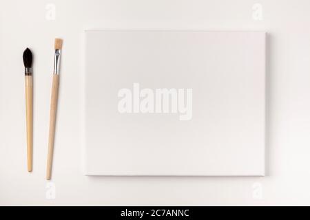Toile de peinture vierge et pinceaux isolés sur fond blanc. Concept d'éducation à la peinture. Vue du dessus. Banque D'Images