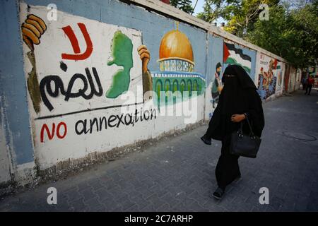 Gaza, Palestine. 14 juillet 2020. Une palestinienne passe devant une fresque de protestation du plan d'Israël d'annexer des parties de la Cisjordanie occupée par Israël, à Rafah, dans le sud de la bande de Gaza, le 15 juillet 2020. (Photo par Yousef Masoud/INA photo Agency/Sipa USA) crédit: SIPA USA/Alay Live News Banque D'Images