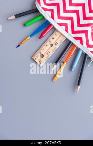 Trousse à crayons pour enfants avec fournitures scolaires disposition de pose à plat sur fond gris Uni Banque D'Images