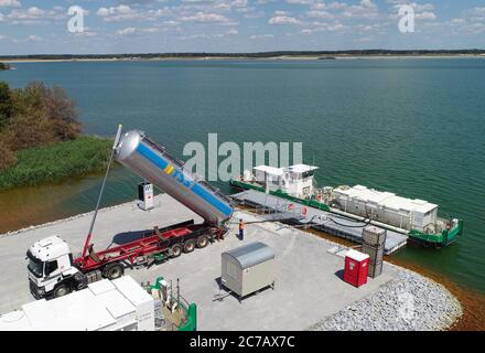 14 juillet 2020, Brandebourg, Sedlitz: Le navire de traitement d'eau 'Klara' du Lausitzer und Mitteldeutsche Bergbau-Verwaltungsgesellschaft mbH (LMBV) est chargé de chaux sur les rives du lac Sedlitz (photographie aérienne prise avec un drone) la mine ouverte Sedlitz est limée depuis juin au nom du LMBV. Cette neutralisation initiale est effectuée avec le navire de traitement d'eau 'Klara' du LMBV, qui était déjà en service sur le lac Partwitz. La mesure devrait être réalisée d'ici la fin du mois de septembre. Environ 10,000 tonnes de chaux vive seront alors introduites Banque D'Images