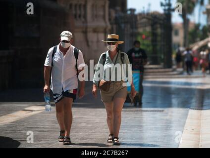 Malaga, Espagne. 15 juillet 2020. Un couple de touristes portant des masques de visage marchant dans les rues pendant le premier jour de l'utilisation obligatoire des masques de visage. De nouvelles infections à coronavirus en Espagne après l'assouplissement des restrictions ont amené le gouvernement régional à imposer l'utilisation obligatoire de masques faciaux en plein air et dans les lieux fermés et les plages, même lorsqu'ils observent une distance de sécurité entre les gens. Cette mesure vise à freiner la propagation de la pandémie du coronavirus. Crédit : SOPA Images Limited/Alamy Live News Banque D'Images