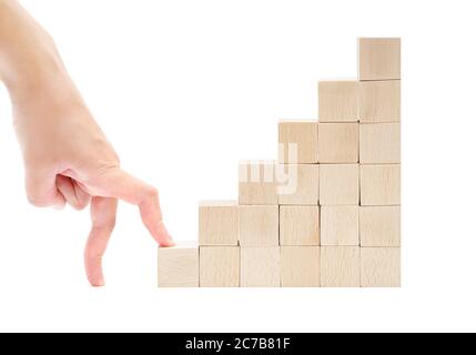 Les doigts commencent à grimper les escaliers en blocs de jouets en bois isolés sur fond blanc. Première étape sur le concept de l'échelle de carrière. Banque D'Images