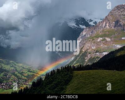 Photo aérienne d'un arc-en-ciel se brisant derrière un nuage de tempête dans la vallée alpine de Grindelwald en Suisse. Banque D'Images