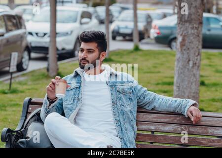 Un homme indien élégant qui boit un café à emporter dans la rue. Banque D'Images