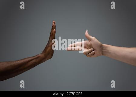 Arrêtez l'alésage. Tolérance raciale. Respecter l'unité sociale. Des mains africaines et caucasiennes sur fond gris de studio. Droits de l'homme, amitié, concept d'unité intenationale. Unité interraciale. Banque D'Images