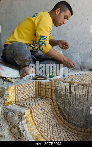 Homme marocain travaillant sur une mosaïque de décoration dans une poterie à Fès, Maroc Banque D'Images