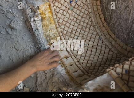 Main de l'homme marocain travaillant sur une mosaïque de décoration dans une poterie à Fès, Maroc Banque D'Images