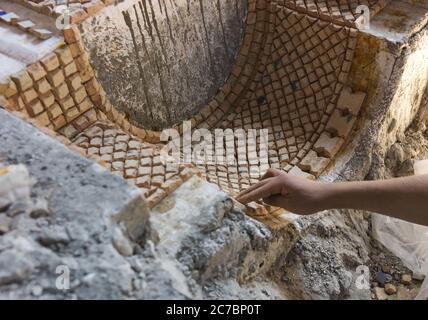 Main de l'homme marocain travaillant avec la céramique sur une mosaïque de décoration dans une poterie à Fès, Maroc Banque D'Images