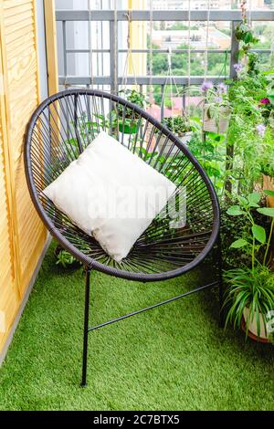 Chaise de jardin avec oreiller sur le balcon à la maison dans l'appartement sur pelouse herbe avec plantes de la maison fleurs. Véranda du jardin terrasse moderne. Jardinage à la maison Banque D'Images