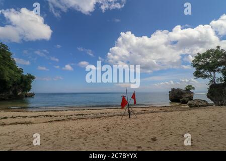 Il est dangereux de nager dans les vagues de l'océan. Drapeau rouge flottant au vent sur la plage au temps orageux Banque D'Images