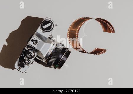Set de pose plat géométrique : caméra vintage sur arrière-plans clairs avec pellicule de 35 mm. Vue de dessus. Banque D'Images