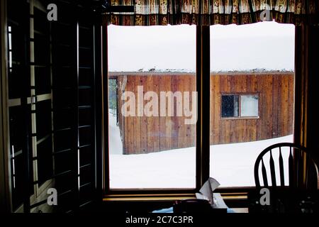 Belle photo de l'intérieur d'une maison où un hangar en bois couvert de neige est visible Banque D'Images