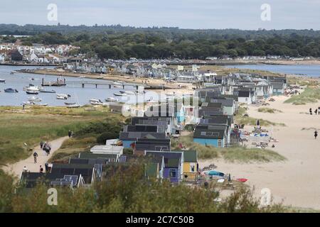 La plage se trouve sur la rive de sable de Mudeford, Dorset, tandis que les gens se dirigent vers la plage. Banque D'Images