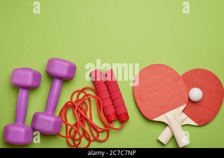 baskets, corde à sauter et raquettes en bois pour le tennis de table sur fond vert, place pour une inscription, plat Banque D'Images