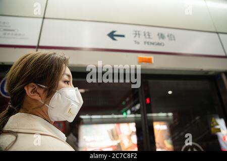 Le port d'un masque de la jeune femme se tenait sur la plate-forme du métro Banque D'Images