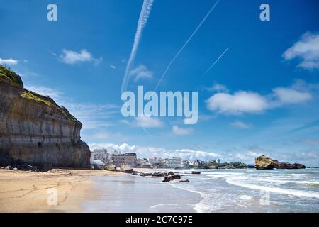 Biarritz et ses célèbres plages de sable. Pierres, vagues de l'océan. Côte Atlantique, pays Basque, France. Jour ensoleillé d'été et ciel bleu avec airpl blanc Banque D'Images