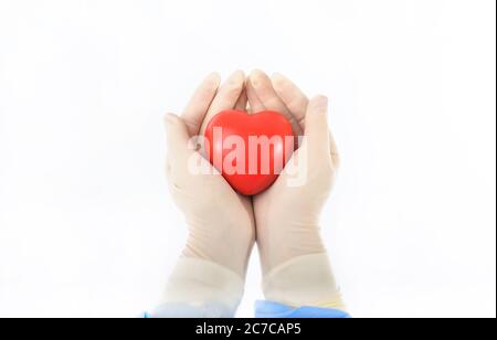 ballon en mousse anti-stress avec forme de coeur par les mains des femmes dans des gants stériles Banque D'Images