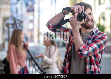 Un gars en chemise à carreaux qui photographie sur un appareil photo dans la rue. Banque D'Images