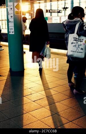 Plan vertical de personnes sur une gare avec un Femme portant un sac qui dit que le surf est génial Banque D'Images