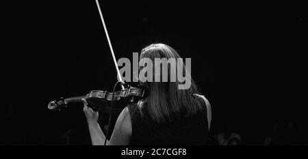 Prise de vue en niveaux de gris d'une femme jouant le violon pour le public Banque D'Images