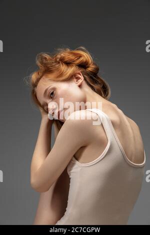 Rêves. Portrait de mode de la belle femme à tête rouge isolée sur fond gris studio. Concept de beauté, de soins de la peau, de mode et de style. Œuvres d'art, portrait moderne et tendance. Modèle attrayant. Banque D'Images