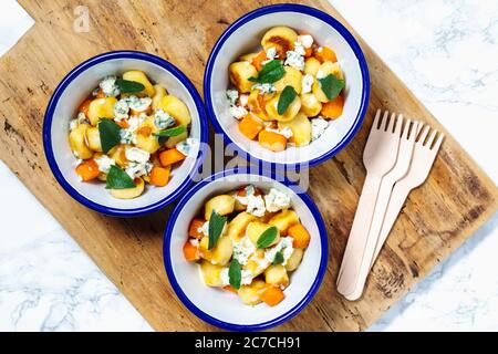 Prise de vue en hauteur de plats avec pommes de terre et légumes en tranches bols blancs sur un plateau en bois Banque D'Images