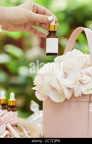 Image rapprochée d'une femme d'affaires mettant une bouteille d'huile essentielle dans une boîte de fleurs lors de l'emballage de la commande pour le client Banque D'Images