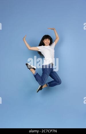 Sautant, semble émotionnel, heureux, gai. Portrait de la jeune femme asiatique isolée sur fond bleu. Belle petite fille mignonne. Émotions humaines, expression faciale, ventes, publicité, concept d'achat en ligne. Banque D'Images