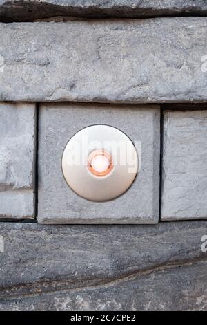 Bouton de porte éclairé avec cadre en plaqué or sur une façade en pierre Banque D'Images