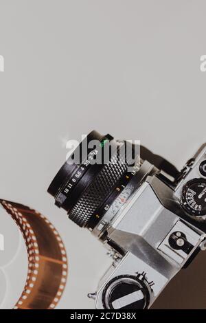 Set de pose plat géométrique : caméra vintage sur arrière-plans clairs avec pellicule de 35 mm. Vue de dessus. Banque D'Images