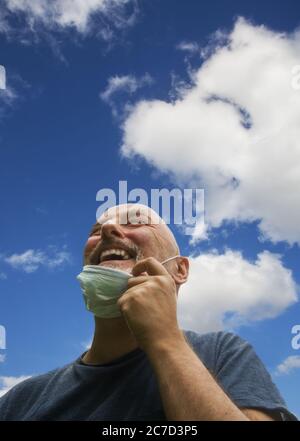 Heureusement et joyeux, enlève son masque, respirer l'air frais regardant vers le ciel.les restrictions du virus Corona sont assouplies et il n'a plus toujours besoin Banque D'Images