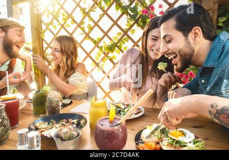 Des amis heureux se sont régalés avec des repas sains dans le bar-café brunch - les jeunes ont mangé et bu des smoothies fruits frais au restaurant Banque D'Images