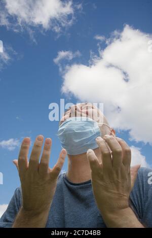 Heureusement et joyeux, enlève son masque, respirer l'air frais regardant vers le ciel.les restrictions du virus Corona sont assouplies et il n'a plus toujours besoin Banque D'Images