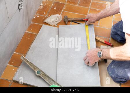 Le carreleur mesure les carreaux avant qu'elle coupe Banque D'Images