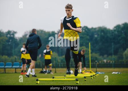 Adolescent joueur de football en entraînement. Jeunes joueurs de football à la séance d'entraînement avec entraîneur. Un joueur de football qui saute sur les haies. Garçons courant jeunes Agili Banque D'Images