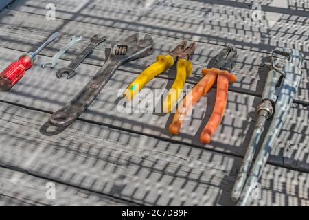 Un jeu de divers outils de construction et de ménage, tournevis, clés, pinces, sur un plancher en bois Banque D'Images